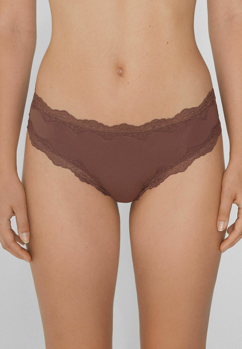 Culottes marron avec des bordures en dentelle, présentant une texture de tissu lisse et des bords festonnés, dotées d'une taille mi-haute pour une forme ajustée.