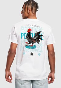 Balts T-krekls ar lielu krāsainu gaili, futbola bumbu un tekstu "Portugāle" zilā krāsā. Vienkārša apaļa kakla izgriezuma un īsas piedurknes.