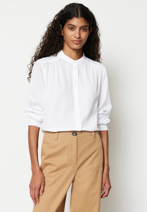 Witte lange mouwen button-up shirt met een bandkraag, geplooide details bij de schouders, gecombineerd met beige hoge taille broek met een voorzak.