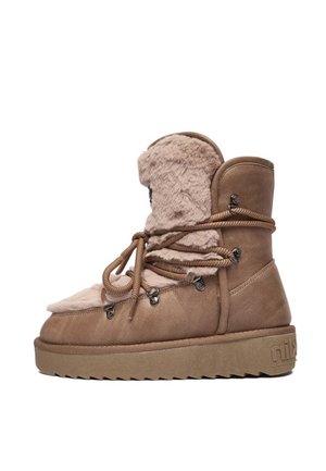 Bota de invierno marrón con suela gruesa, forro de piel y cordones de cuerda envueltos alrededor del tobillo, mostrada de lado sobre un fondo blanco.