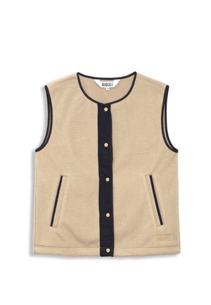 Chaleco de forro polar en beige con cuello redondo, ribete negro, cierre frontal a presión y dos bolsillos laterales. Presenta una etiqueta de logo en la parte inferior derecha.