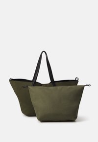 Olivgrüne Stofftaschen mit schwarzen Griffen; eine Tasche ist leicht größer und hat einen Reißverschluss, beide haben eine strukturierte Form.