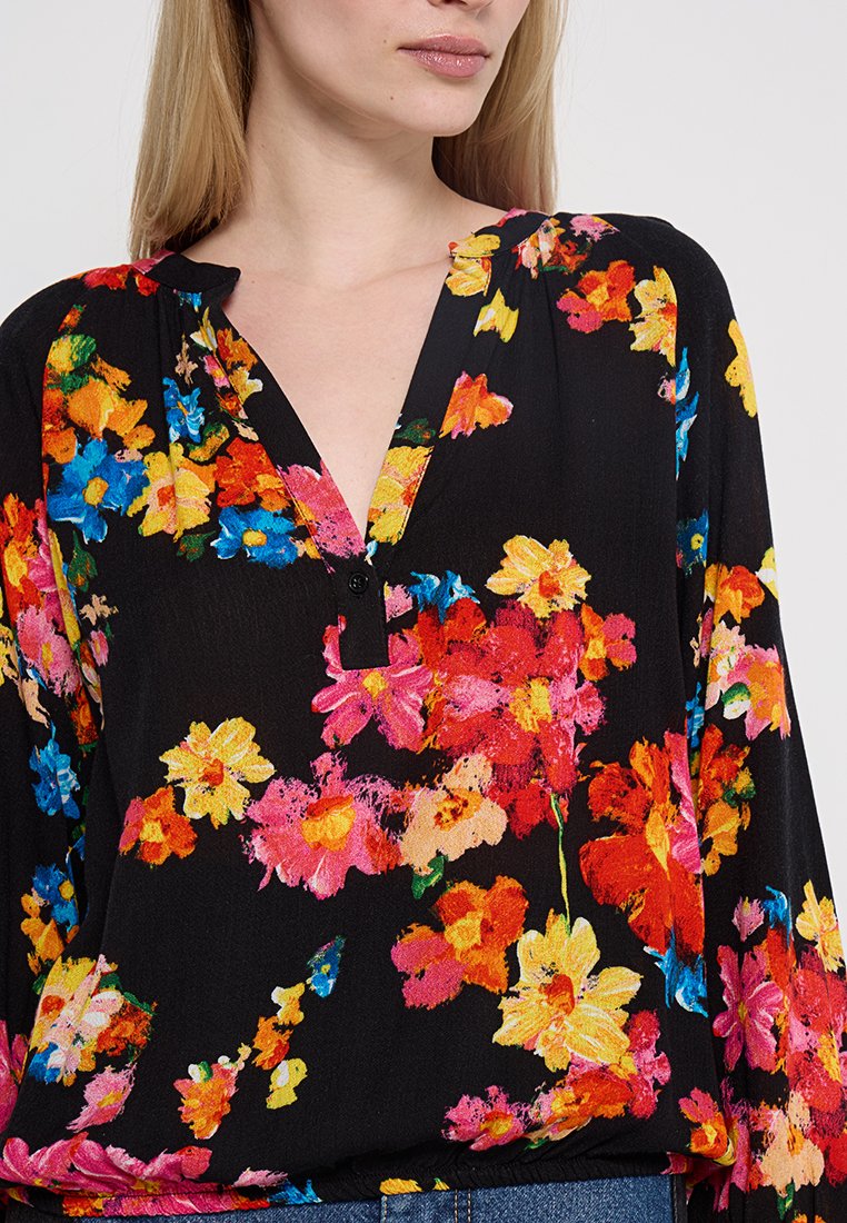 Czarna bluzka w kwiaty z jaskrawymi, wielokolorowymi kwiatami w odcieniach różu, żółci i niebieskiego, z dekoltem w kształcie litery V oraz detalami z guzikami.
