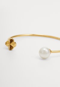 Pulseira de vinte em ouro com um destaque em forma de trevo e uma pérola redonda e lisa. Design elegante com um acabamento polido.