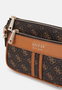 Hnědo-černá křížová taška s vzorem s pozlacenými detaily, dvěma zipovými kapsami a logem v embosovaném písmu.