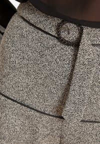 Grauer und schwarzer Textilstoffrock mit einem runden schwarzen Hardware-Akzent an der Taille und schlankem schwarzen Besatz entlang der Nähte.
