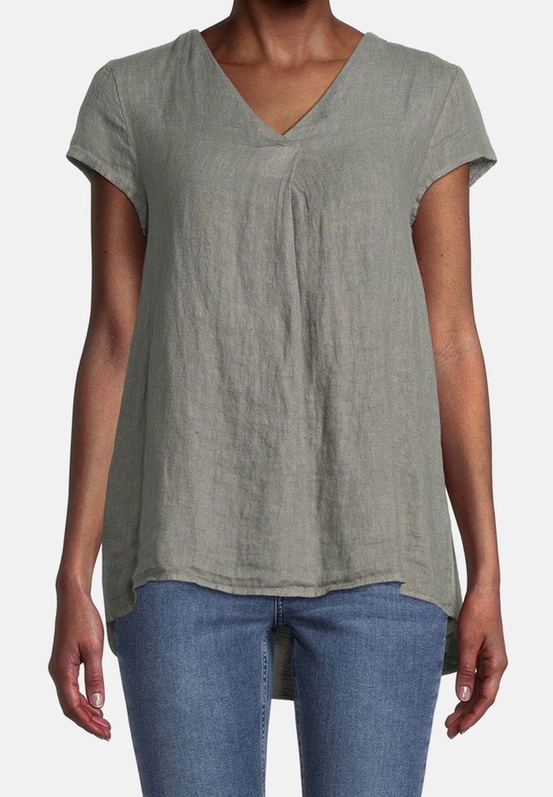 Haut en lin vert clair avec des manches courtes, un col en V et un dos légèrement plus long. Il présente une coupe décontractée et une texture douce.