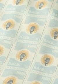 Katoenen stof met een herhalend patroon van postzegelontwerpen in blauw, geel en grijs, met zonnestralen en gestileerde schedelmotieven.