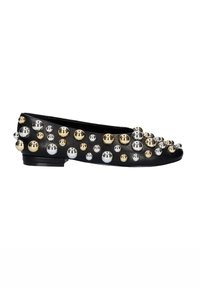 Zapato plano de cuero negro que presenta audaces tachuelas metálicas en oro, plata y cromo, adornando la parte superior y el área de la punta redonda.