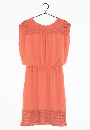 Koralfarvet ærmeløs kjole med blomsterblonde detaljer på skuldre og kant, elastisk talje, hængende på en sort bøjle mod en hvid baggrund.