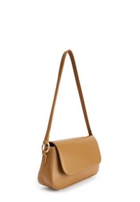 Tan leren schoudertas met klep en gouden ringdetail op de strap tegen een witte achtergrond.