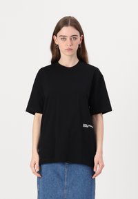 Svart bomullst-skjorte med rund hals og korte ermer. Har hvit "Karl Lagerfeld Jeans" branding på siden. Enkelt, avslappet snitt.