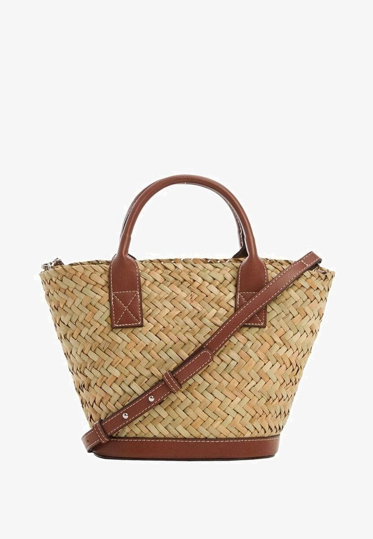 Sac fourré en paille avec poignées en cuir marron et bandoulière. Caractéristiques : forme ronde, texture naturelle et accents beige.