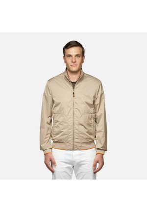 Giacca bomber beige con zip frontale, due grandi tasche e dettagli arancioni sui polsini e sul cinturino. Realizzata in tessuto leggero e liscio.