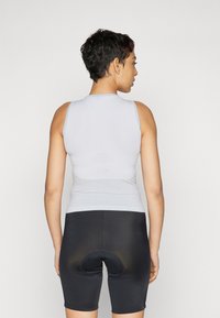 Helles graues, ärmelloses Oberteil mit gerippter Textur, kombiniert mit schwarzen, eng anliegenden Shorts mit gepolstertem Bereich.