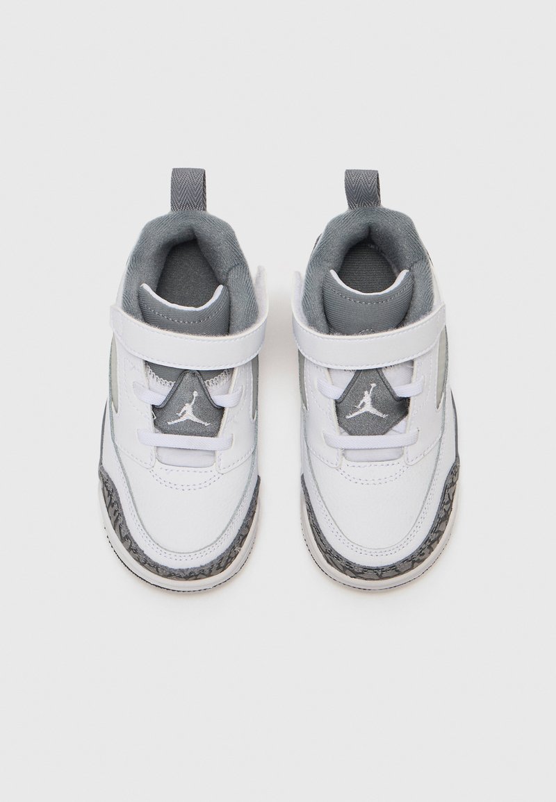 Witte sneakers met grijze accenten, voorzien van een gestructureerde zwart-witte zool, klittenbandsluiting en een driehoekig logo op de tong. Zacht binnenin.