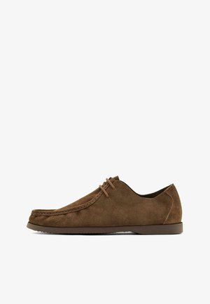 Chaussure décontractée pour homme en daim marron à lacets, avec pointe mocassin cousue et semelle en caoutchouc basse, montrée de profil sur fond blanc.