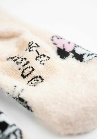 Calzini pastello rosa fuzzy con motivi e dettagli di gatti in bianco e nero. Superficie strutturata per il comfort con un aspetto accogliente.