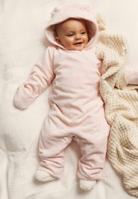 Roze fleece overall met berenoren op de capuchon, bloemenpatroon en elastische manchetten. Vergezeld van een lichte gebreide deken.
