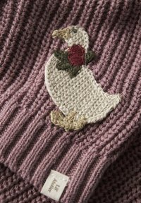 Pletená tkanina v mauve barvě s žebrovanou strukturou; zdobena vyšitým bílým kachním motivem se zelenými listy a červenou růží, a malou značkovou štítkem.