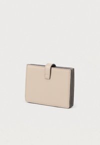 Bézs bőr kártyatartó sima textúrával, kompakt téglalap alakú, fedeles záródással. Több kártyazsebbel a szélén.