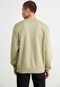 Olivengrønt sweatshirt lavet af blødt stof, med rund hals, ribbede manchetter og forstænger, i en afslappet pasform og minimalistisk design.