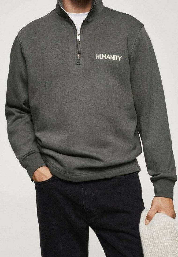 Sweat-shirt gris à fermeture éclair en tissu doux, avec des poignets et un ourlet côtelés, arborant "HUMANITY" brodé en couleur claire sur la poitrine.