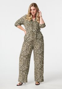 Combinaison à motifs en beige et vert foncé ; dotée d'un design enveloppant, de jambes larges et d'une taille ceinturée. Tissu doux et texturé avec des manches 3/4.
