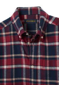 Rotes und marineblaues kariertes Hemd aus weichem Stoff mit Kragen, weißen Knöpfen und einer Brusttasche mit dezentem Fischgrätenmuster.