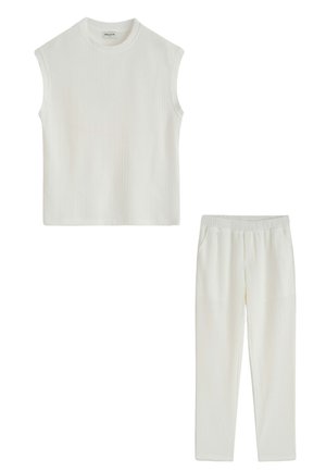 Haut blanc sans manches en maille côtelée associé à un pantalon en maille côtelée avec taille élastique assorti.