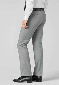 Graue, maßgeschneiderte Hose aus einem strukturierten Stoff, mit klassischer Passform, flachem Frontbereich und hinten geknöpften Taschen. Getragen mit schwarzen Slippern.