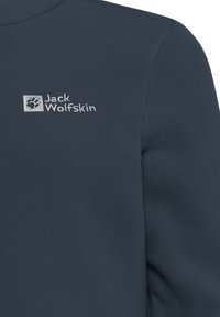 Giacca in pile blu scuro con una texture morbida. Presenta un logo argento, "Jack Wolfskin," con un emblematico impronta di zampa. Design semplice e senza fronzoli.