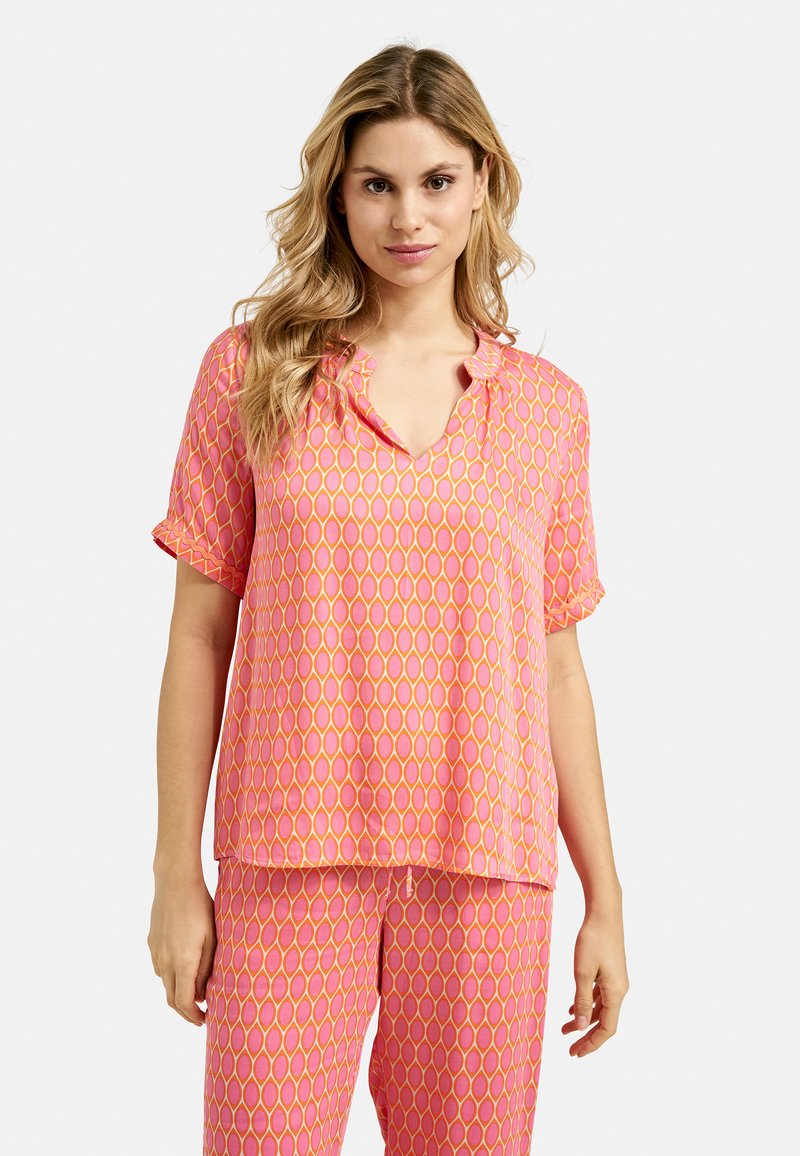 Rosa Schlafanzugset, bestehend aus Bluse und Hose. Die Bluse hat einen V-Ausschnitt und kurze Ärmel sowie ein ovales Muster in Gelb und Rosa. Weicher Stoff.