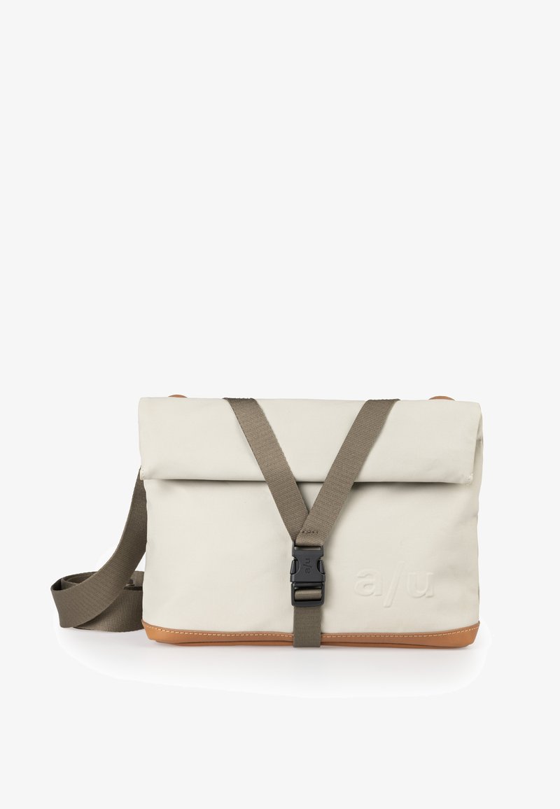 Borsa a spalla in tessuto color crema con base in pelle marrone chiaro. Presenta un lembo pieghevole, una tracolla regolabile e una chiusura con fibbia in plastica.