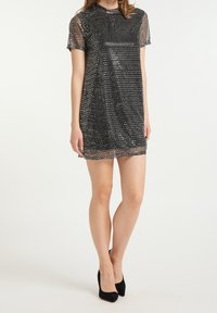 Svart paljettklänning med genomskinliga korta ärmar, rund halsringning och rak passform. Tyget har en glansig finish som framh äver paljetternas glans.