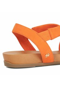 Orange sandal with soft suede straps, featuring a molded tan footbed and a logo accent on the side. Flat, lightweight design.