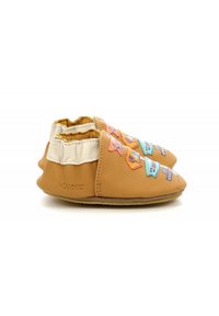 Zapatos de cuero marrón claro con parches de tela coloridos, acentos blancos y una textura suave. Presentan una suela flexible y detalles cosidos.