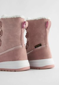 Rosa wasserdichte Stiefel mit einem weichen weißen Fellfutter, glattem Wildledermaterial, runder Zehenform und einer strukturierten weißen Sohle. Mit Schnürdesign.