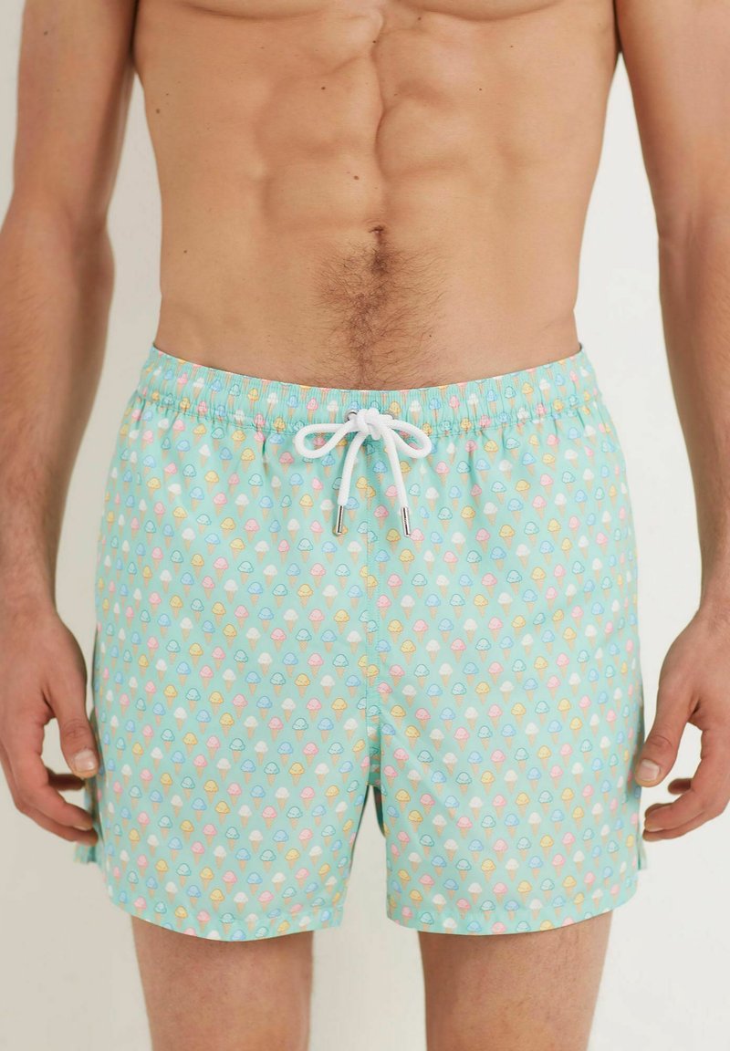 Pantaloni de baie cu un fundal albastru deschis și un model colorat cu cornete de înghețată. Confectionați dintr-un material ușor, cu talie elastică și șnur de strângere.