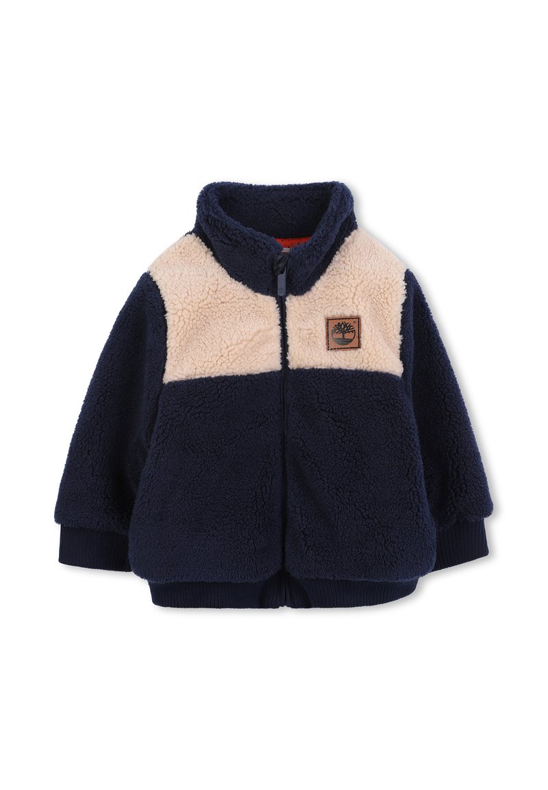 Giacca di pile navy e beige con zip, colletto alto, polsini a coste e un piccolo logo a patch marrone sul petto.