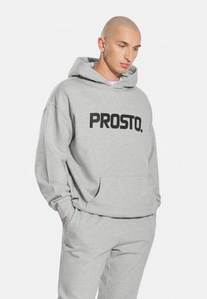 Szara bluza z kapturem wykonana z miękkiego materiału, z dużym czarnym logo "PROSTO." na przodzie, z kapturem na sznurku i kieszenią kangurkową.