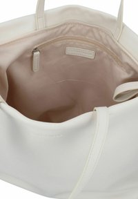 Witte tote bag gemaakt van glad materiaal, met een ruime binnenkant voorzien van een lichtbeige voering en een ritsvak.