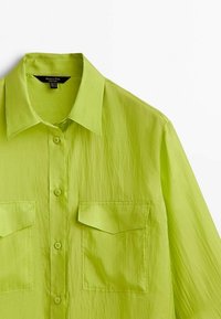 Lime green button-up shirt made of lightweight fabric, featuring two chest pockets, a folded collar, and a relaxed fit.