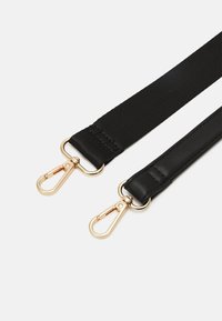 Sangle noire composée d'un mélange de tissu texturé et de cuir lisse, avec des clips en métal doré pour l'attache à chaque extrémité.