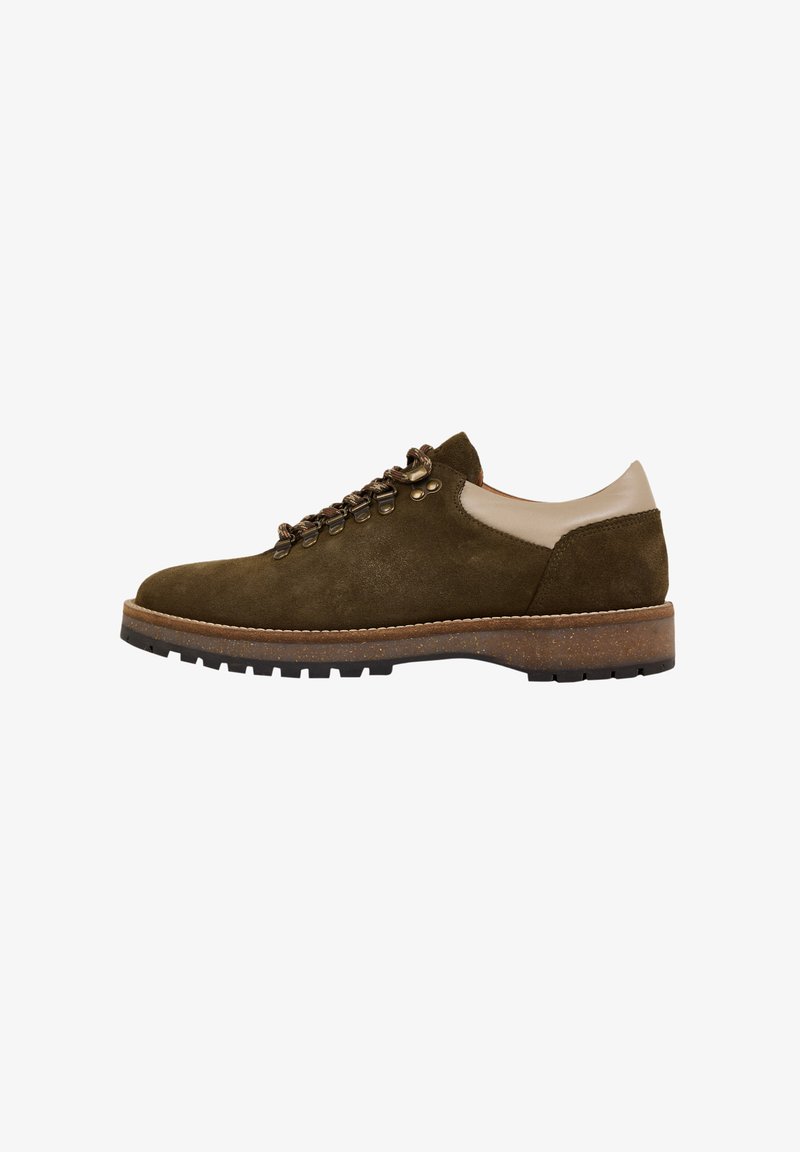 Chaussure en daim vert olive avec des accents en cuir beige, design à lacets, œillets en métal et semelle en caoutchouc texturé brun.