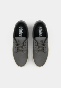 Sneaker in canvas grigio con suola in gomma bianca, design con lacci e soletta nera con il marchio "etnies". Costruzione semplice e leggera.