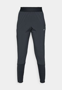 Dunkle graue Nike Sporthosen mit einem schmal zulaufenden Bein-Design, elastischem Bund und Akzentdetails in der Nähe der Bündchen.