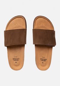 Bruine suède slidesandalen met een brede band en een zachte, tan kleurige binnenzool. Heeft een lichte kromming bij de tenen en een platte zool.