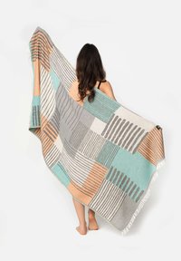 Coperta multicolore con un motivo geometrico in grigio, teal, arancione e crema. Realizzata in un tessuto morbido con bordi frangiati.