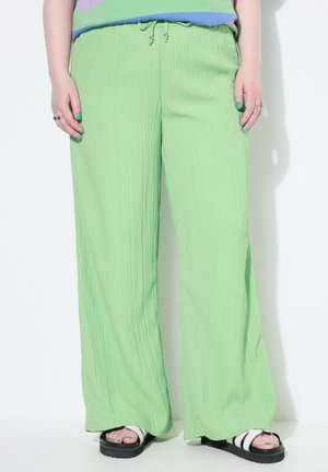 Lichtgroene wijde broek met een textuurstof, voorzien van een verstelbare taille en een ontspannen pasvorm. Gemaakt in combinatie met platte sandalen.